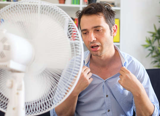 Man sweating infront of a fan - sweat cools us down because it takes energy to turn a liquid to a gas
